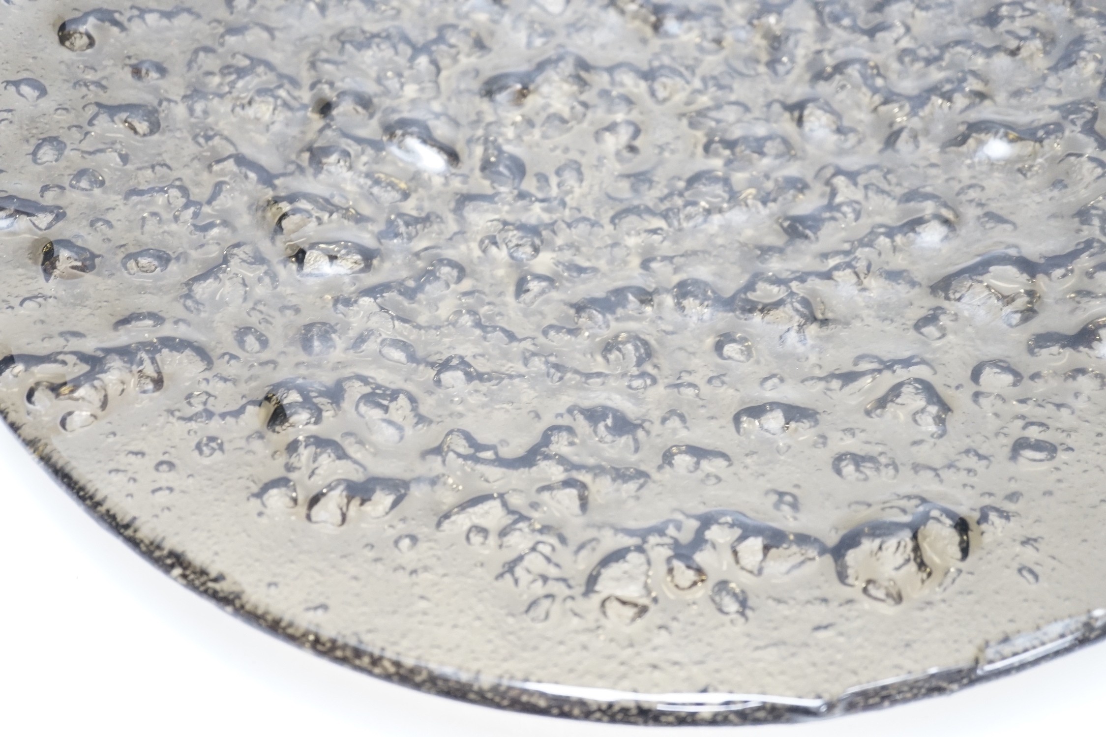 A large rubber-based pewter-coloured glass dish, 48cm